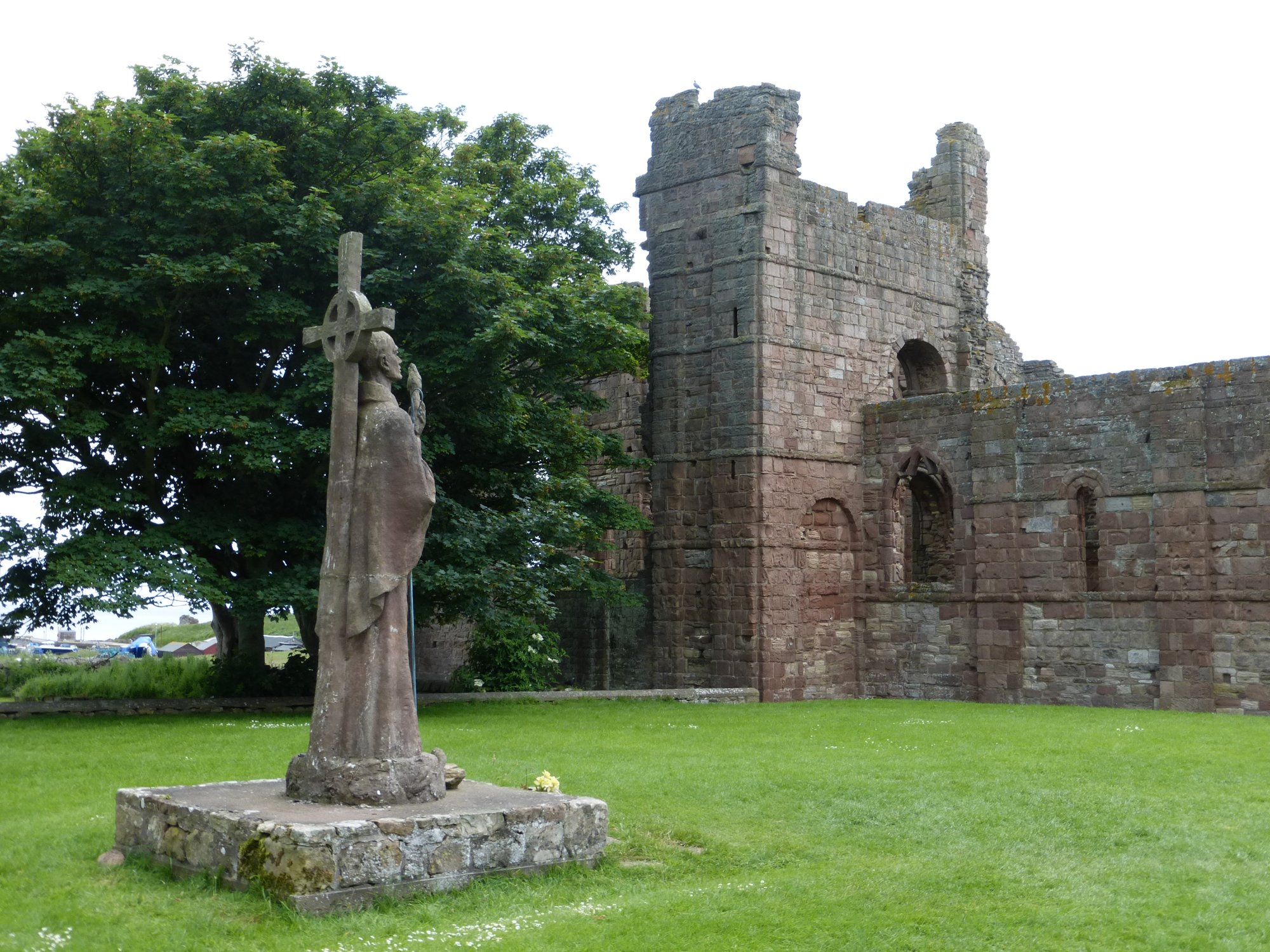 Ruins of Lindisfarne Priory and the statue of St. Aidan, Holy Island, Northumberland, England