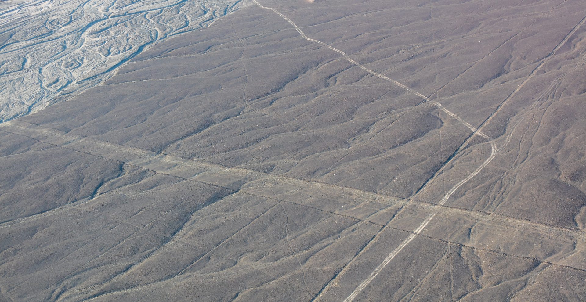 Aerial photograph of the Nazca Lines showing long straight geoglyph lines crossing the Pampa Colorada desert in southern Peru