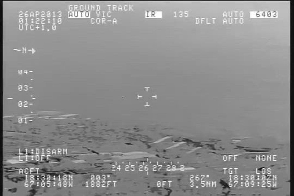 Original mid-wave infrared frame from the April 25-26, 2013 U.S. Customs and Border Protection FLIR video over Rafael Hernández Airport, Aguadilla, Puerto Rico, showing the sensor's targeting reticle on the faint object near the coastline with onscreen date/time and ground-track telemetry