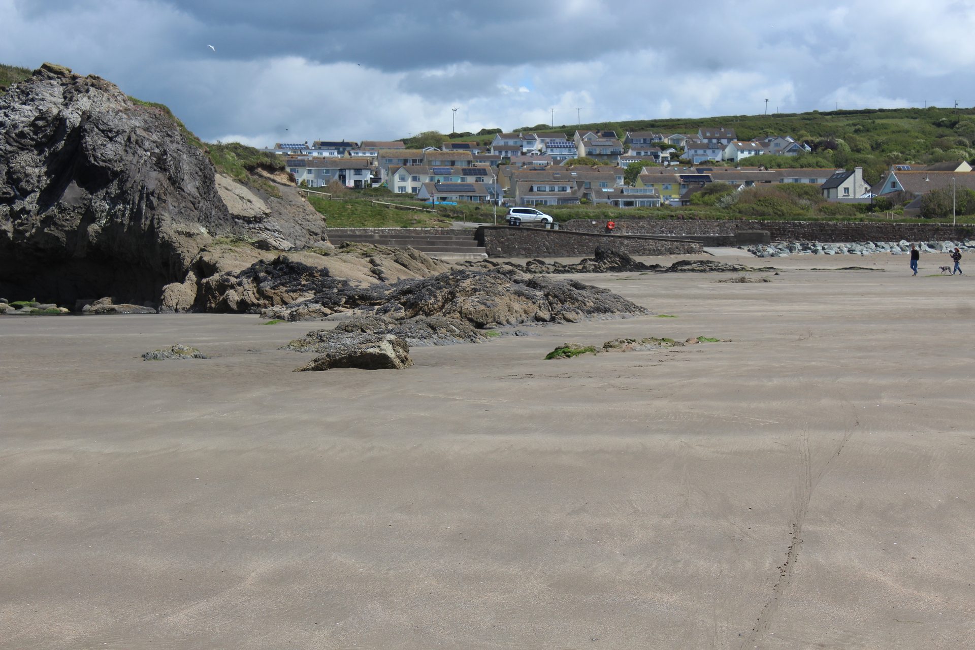 The beach at Broad Haven, Pembrokeshire, Wales, looking across the sand and rock formations of St Bride's Bay. This photograph shows the modern village and coastline, not the school playground or the field where the 1977 sighting occurred, and not the object or figure reported by the children.
