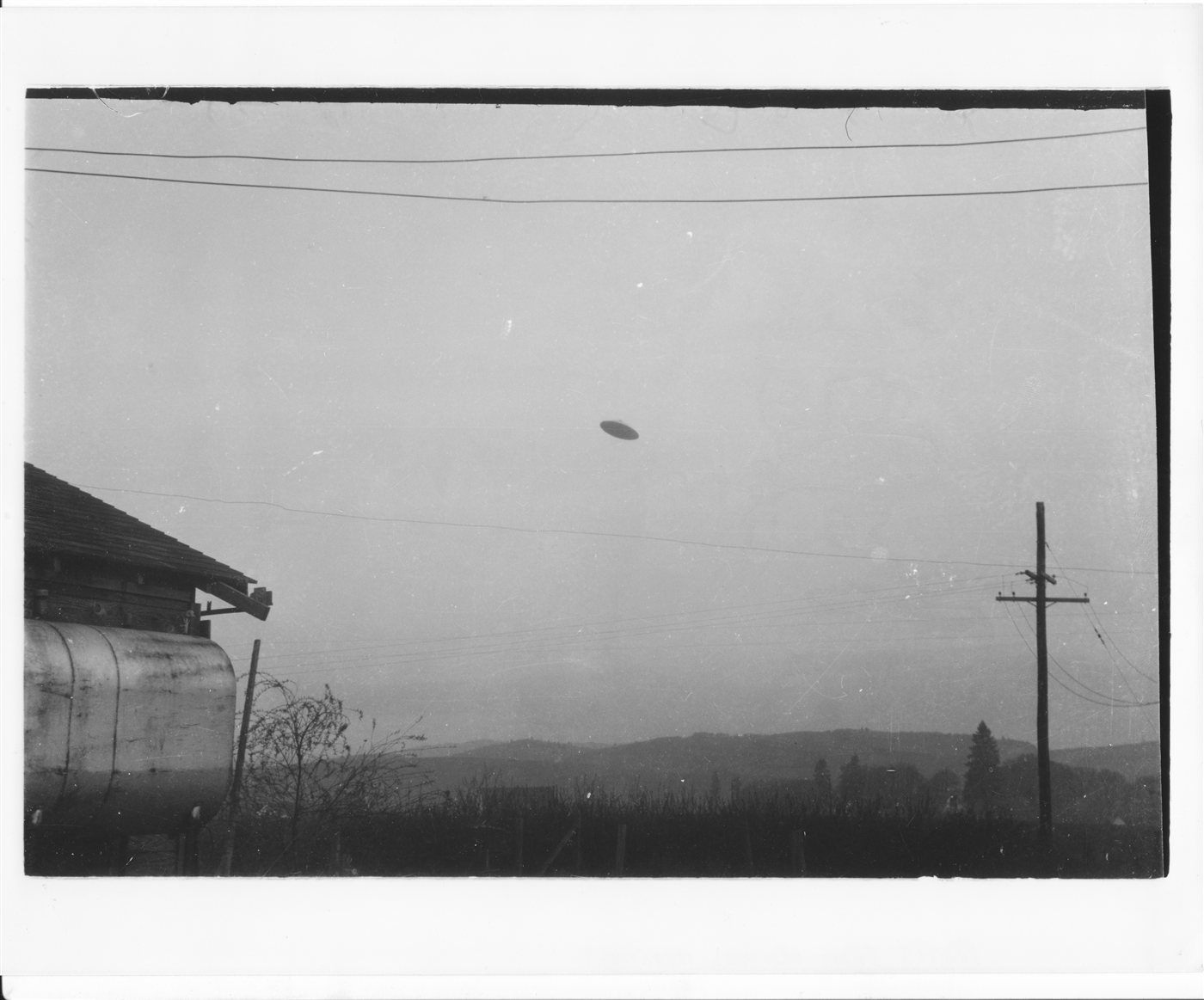One of the two original Trent photographs of the McMinnville, Oregon UFO, taken May 11, 1950 — the object appears above the garage and overhead wires of the Trent farm