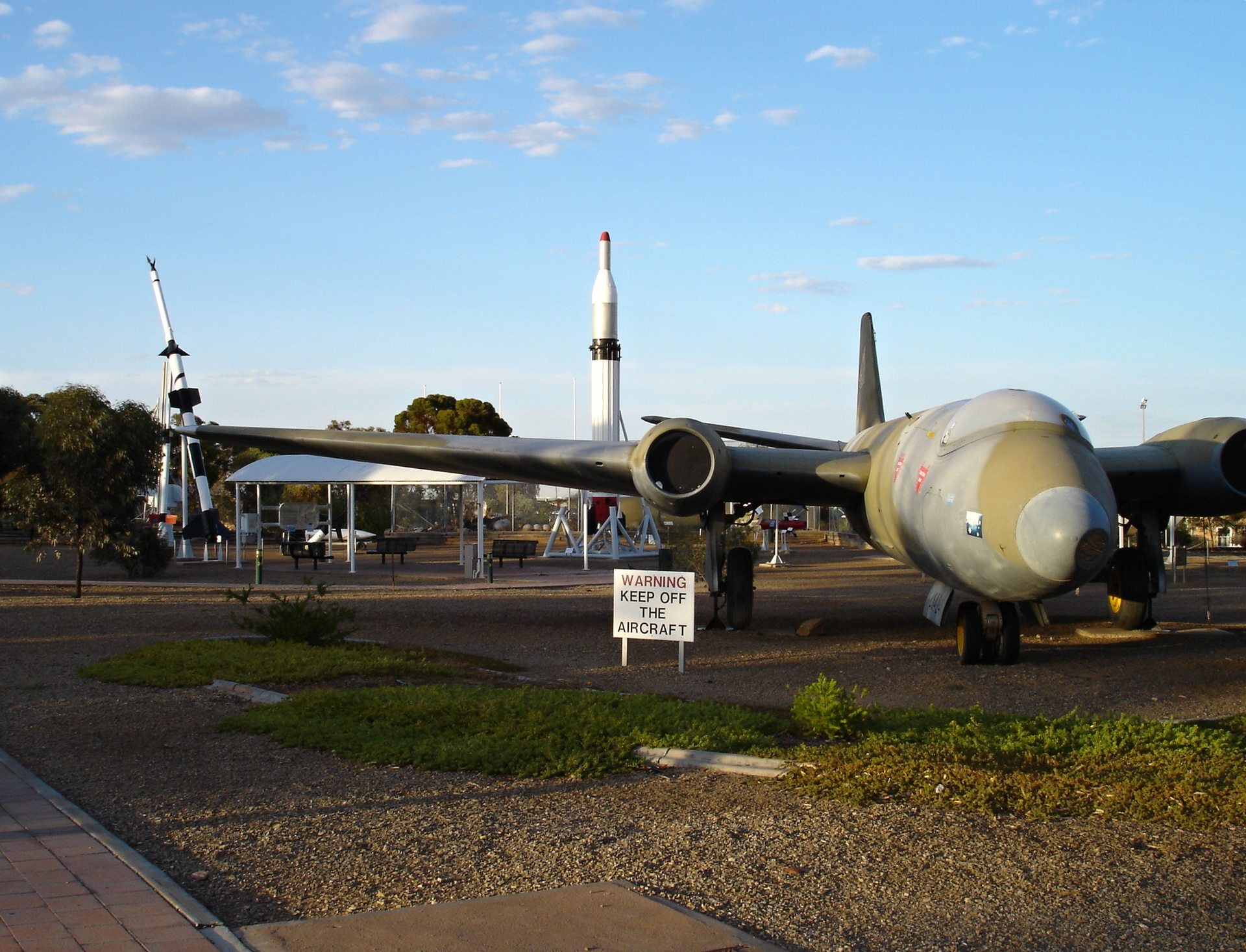 A preserved English Electric Canberra bomber, the same aircraft type whose flight path the object crossed during the May 5, 1954 sighting, on outdoor display at the Woomera Heritage & Missile Park in South Australia, with retired test rockets visible in the background